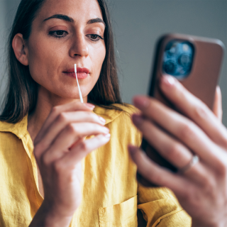 A woman swabs her nostril as part of her at-home COVID-19 test.