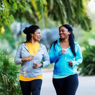 Two women enjoy a walk outside while they talk.