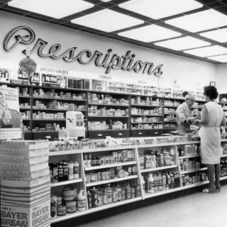 A pharmacist rings up a customer at the register of a neighborhood pharmacy in the 1950s.